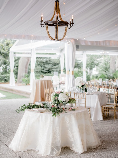 Clear-top tent reception with crystal chandelier and long tables